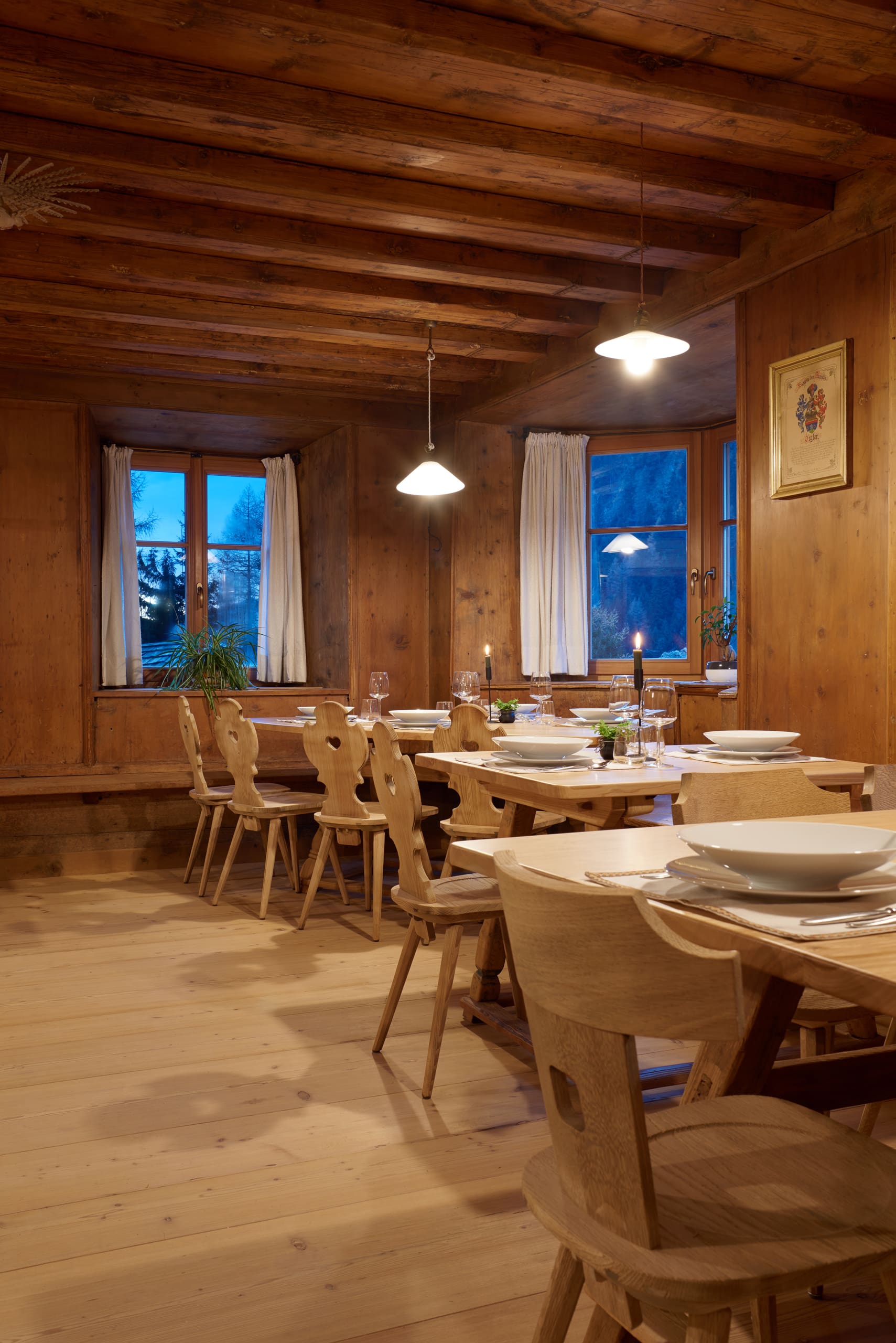 Storica stube della Locanda Wolf con pareti rivestite in legno, soffitto con travi in legno, sedie rustiche e tavoli in legno apparecchiati.